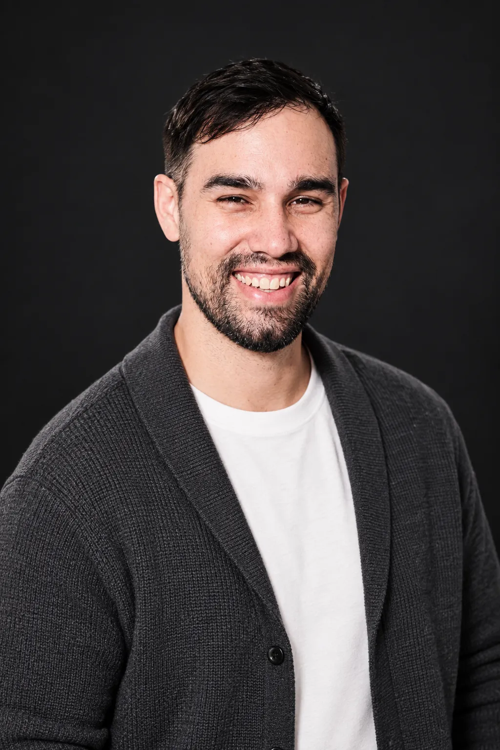 The same man in a charcoal cardigan studio portrait