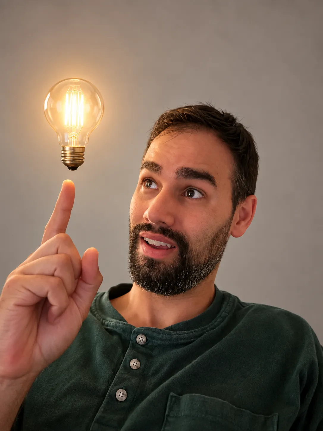 The same man in a warm studio portrait with an Edison bulb overhead